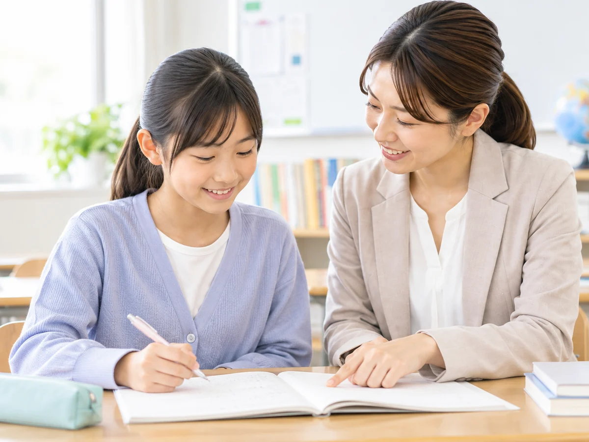 小学生の女子児童が女性教師と学習内容を確認している様子